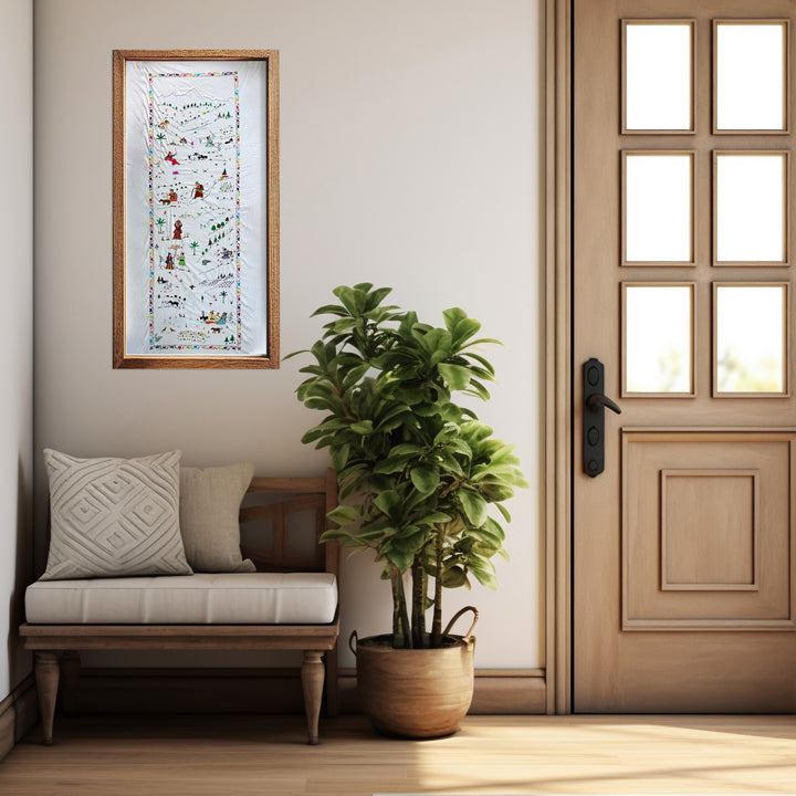 Nestled corner of a room with a wooden bench, potted plant, and framed artwork on a light gray wall.