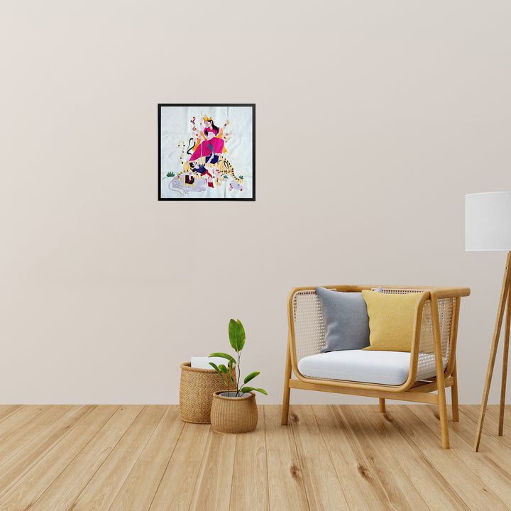 Framed artwork above a wooden chair with cushions in a room with a lamp and plants.