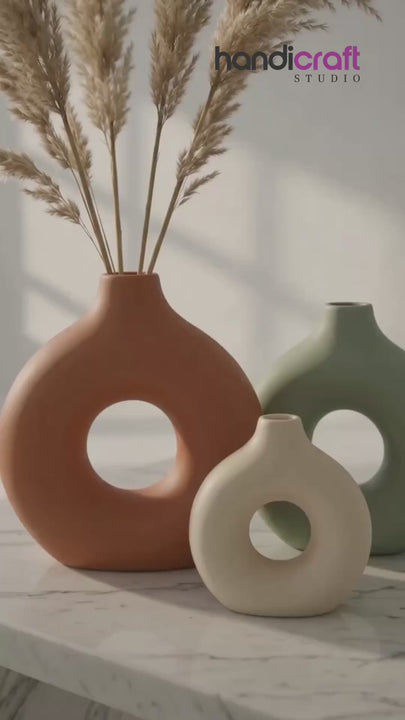 Donut vase in solid muted shades placed on a wooden table in a warm modern living room