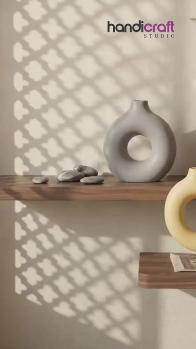 Donut vase ceramic piece in a soft neutral tone resting on a cosy home decor shelf
